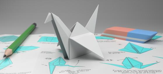 Image d'un origami, un crayon et une gomme posés sur un plan